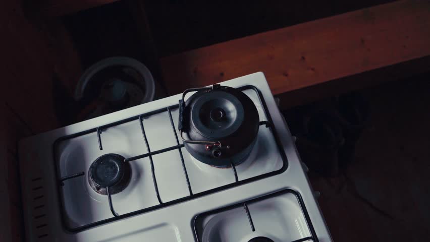 A Man Is Pouring Tea Powder Into A Boiling Kettle Over The Stove. High Angle Shot
