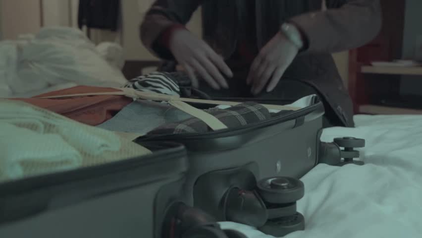 Concept. A woman packing a suitcase or luggage for travel for trip to travel, hands fastening zipper on luggage bag. Tourist zip close up