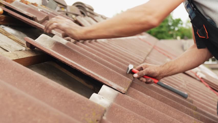 roofer fixes roof with tiles, medium shot of man at work