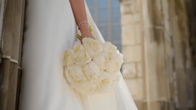 Bride holding white wedding bouquet and wind is waving her dress . - Powered by Shutterstock - Get 15% off with code: PIKWIZARD15