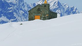 Cappella di San Bernardo chapel with yellow spire, snow-covered mountain backdrop in Cheneil, Aosta Valley, Italy. Aerial drone ascending - Powered by Shutterstock - Get 15% off with code: PIKWIZARD15