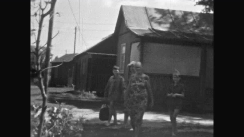 Old archive, Family rural house in summer against backdrop. People family rest in countryside. Grandchildren came to visit grandmother in village for holidays relax. Vintage film. Archival retro 1960s