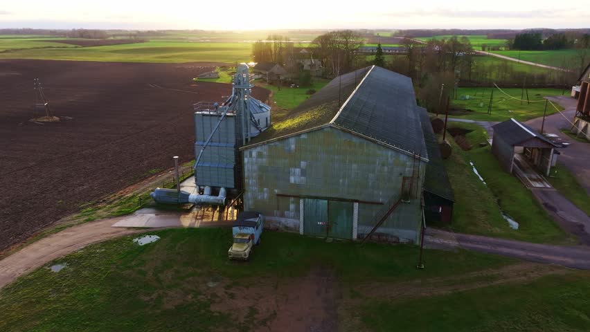 Soviet-built grain dryer, autumn fields and old truck under sunrise in Latvia