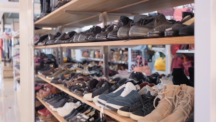 Asia flea market bazaar zero waste eco go green second hand sale store thrift old used vintage fabric retro style city small retail shop. No people shot heap of leather shoe rack shelf.