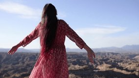 Woman in stylish red dress embracing freedom, standing with raised arms and flowing hair amid expansive desert landscape, experiencing moment of pure serenity - Powered by Shutterstock - Get 15% off with code: PIKWIZARD15