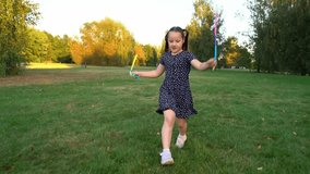 Happy laughing girl runs and jumps rope in summer park at sunset. Children play in nature. Kids leisure outdoors. Playground - Powered by Shutterstock - Get 15% off with code: PIKWIZARD15