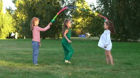 Three happy girls jumps rope and laughs in summer park at sunset. Children fun walk and play in nature. Kids leisure outdoors. Playground - Powered by Shutterstock - Get 15% off with code: PIKWIZARD15