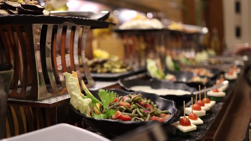 Closeup gourmet buffet with colorful salads juicy cherry tomato skewers and fresh greens artfully arranged on elegant black platters ready to impress guests at upscale catering or hotel dining