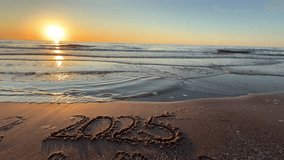 handwritten text of 2025 on a sandy surface at the beach, concept of the New Year, Welcoming the year 2026, Happy New Year. Seashore, waves, sand - Powered by Shutterstock - Get 15% off with code: PIKWIZARD15