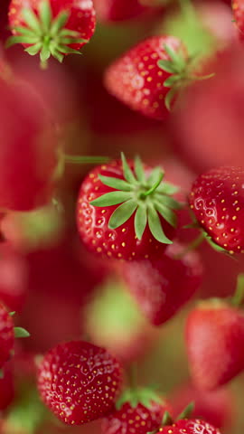 Animation of a group of strawberry. Many strawberry slowly rotate in the background in space. Vertical composition. Defocus. Close-up.