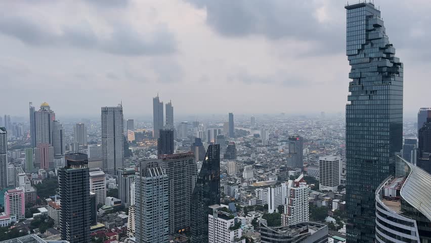 Stunning aerial cityscape view of Bangkok, Thailand, showcasing modern architecture, including the iconic The Mahanakhon skyscraper. The image captures the contrast between towering buildings and a