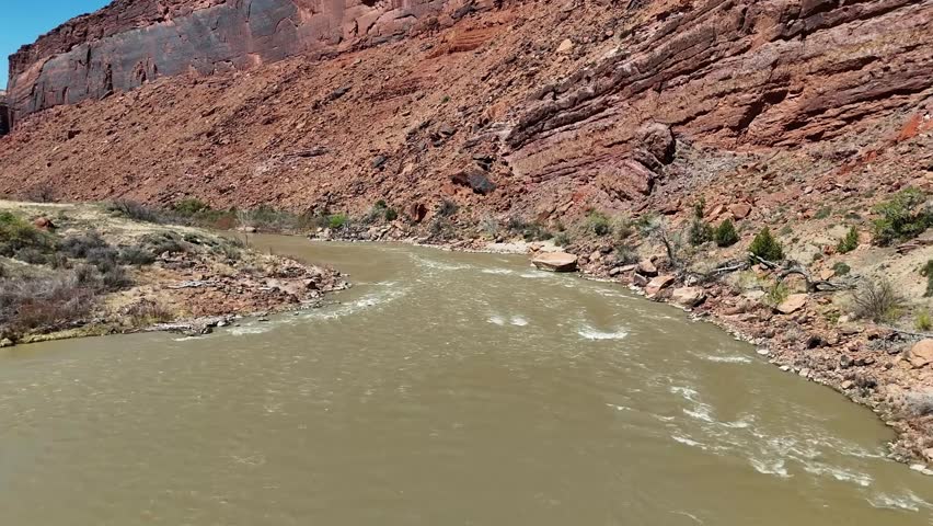 Colorado River in Moab Utah with Small Rapids, Tall Red Sandstone Cliffs, Aerial View, push in shot, Early April