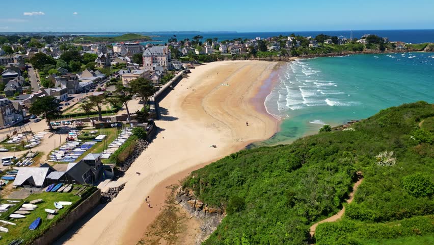 Plage de Saint-Lunaire beach, turquoise waters, coastal town and cliffs, Brittany, France. Aerial drone lateral view