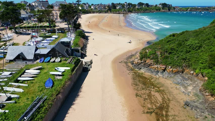 Plage de Saint-Lunaire beach, turquoise waters, coastal town and cliffs, Brittany, France. Aerial drone ascending