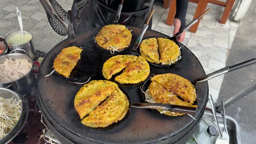 Savory Vietnamese Banh Xeo pancakes sizzling on a hot griddle. Crispy, golden-brown, delicious street food. Close-up view of the cooking process.