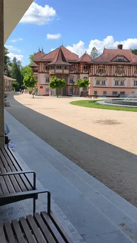 Spa architecture in Luhačovice, Czech Republic, featuring a picturesque historic building with timber framing and a central fountain in a well-maintained square. wellness travel, cultural tourism, 