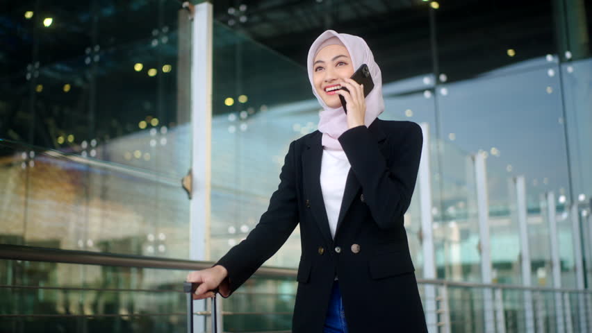 Happy asian muslim business woman wearing hijab using smartphone and walking at airport terminal. Islamic woman people lifestyle travel. Muslim people concept. - Powered by Shutterstock - Get 15% off with code: PIKWIZARD15