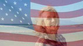 Senior woman on beach smiling, breeze rippling American flag overlay and lifting hair for business. Patriotism, serenity, coastal, leisure, vitality, independence, nature - Powered by Shutterstock - Get 15% off with code: PIKWIZARD15