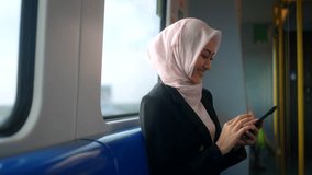 Happy asian muslim business woman wearing hijab holding and using smartphone traveling by railway or skytrain at train station. Islamic woman people lifestyle travel. Muslim people concept. - Powered by Shutterstock - Get 15% off with code: PIKWIZARD15