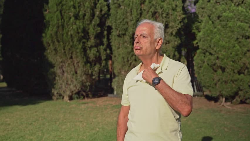 Video of Elderly man wiping sweat in summer heat outdoors