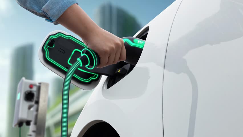 Man insert smart EV charger to electric car and recharging from EV charging station with modern cityscape in background. Futuristic sustainable power and EV car utilization in ESG city. Peruse