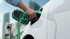 Man insert smart EV charger to electric car and recharging from EV charging station with modern cityscape in background. Futuristic sustainable power and EV car utilization in ESG city. Peruse - Powered by Shutterstock - Get 15% off with code: PIKWIZARD15