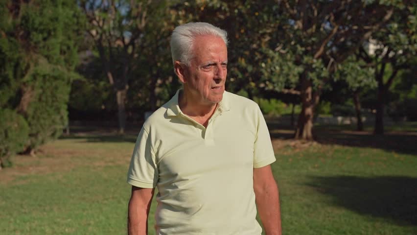 Video of Senior man wipes sweat from face and neck with a tissue in a park during a hot summer day
