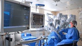 Monitors with life signs of the patient under surgery. Futuristic Da Vinci robot operating the patient under the supervision of male doctor. - Powered by Shutterstock - Get 15% off with code: PIKWIZARD15