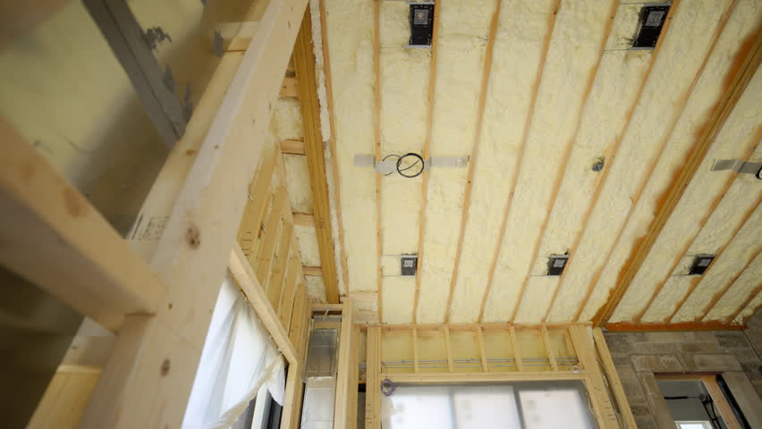 Fiberglass insulation installed between the wooden wall studs in the ceiling or on the construction site. Close up view