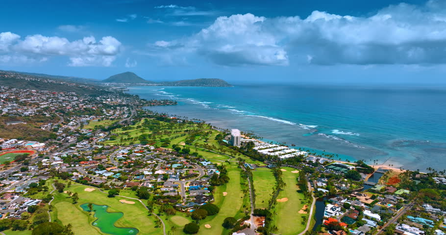 Amazing green shore of the Pacific Ocean with multiple villas. Fluffy cloudscape hanging in the sky above the waterscape. Hawaii. USA. Aerial view.
