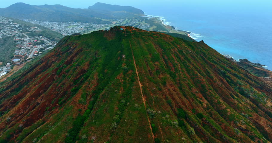 Distancing from the top of the Diamond Head Crater. Inhabited slopes of the mountains at backdrop. Aerial perspective. Honolulu, Hawaii, USA.