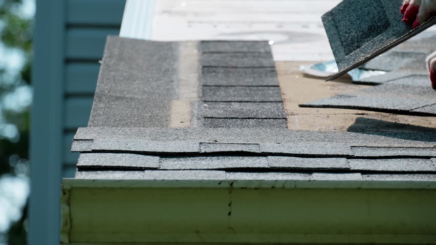 Roofers putting new roof shingles in right order on the house roof. Element of roof renovation