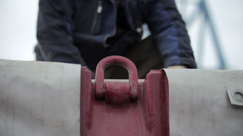 Worker attaching lifting shackle to cargo hook
