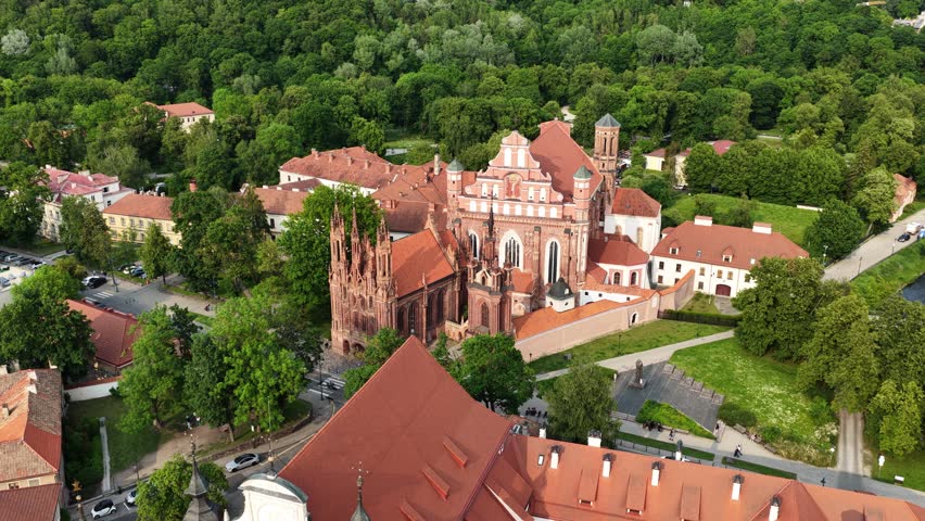 Elevated view of the iconic Gothic and Baroque style church ensemble in Vilnius, nestled among greenery and historic architecture.