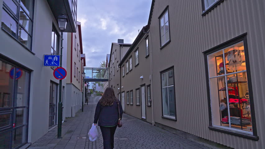 Woman walking alone on empty street in Reykjavik during evening hours