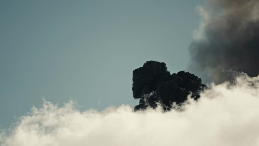 Dark smoke and ashes rise above white clouds, erupting Fuego volcano