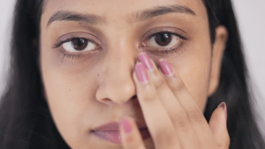 Periorbital dark circle, insomnia, A young lady showing her under eye dark circle in white background, close up shot.
