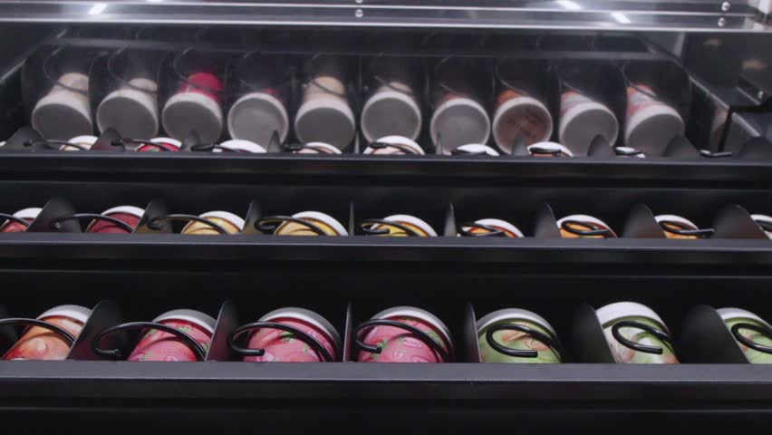 Chilled ice creams and desserts selection in a commercial vending machine fridge with open drawers.