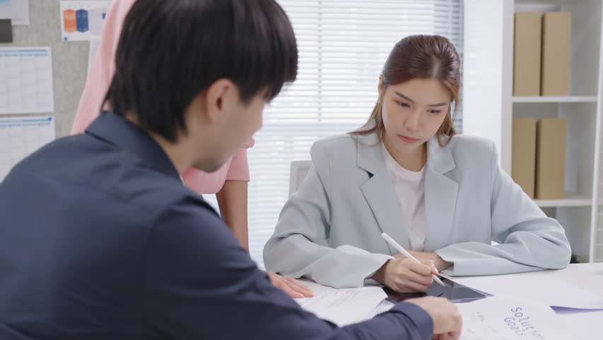 A group of Asian business professionals gathers in a modern office for a focused financial consultation, discussing strategies and analyzing performance data to drive success and business growth