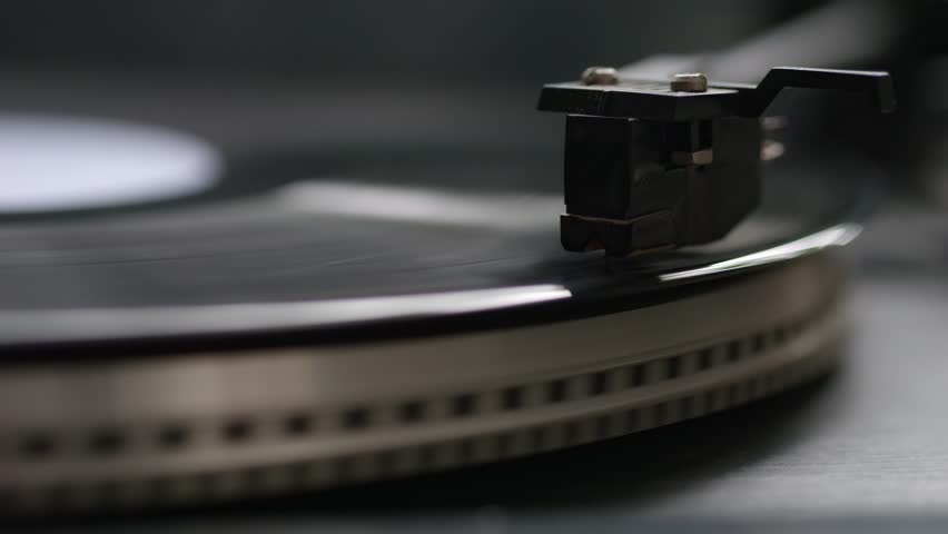 Close-up shot of record player needle tracking vinyl disc, slow rotation visible, perfect as a music-themed visual loop.
