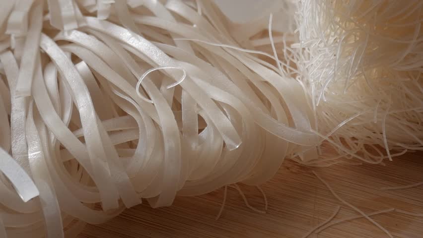 Thin rice noodles, close-up of vermicelli and flat noodles on a wooden surface
