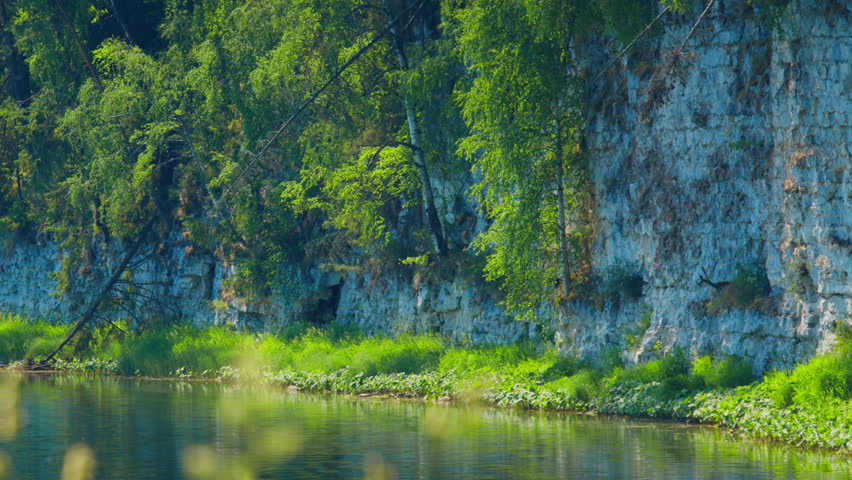 Calm river flows in a mountains with green lush coasts