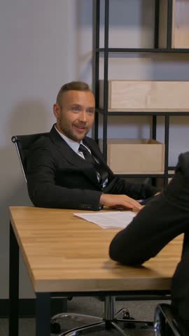 Team of aframerican and caucasian bussinespeople talking during an work meeting looking into the boardroom speaking about deal. Slow motion 4k UHD. Vertical shot.