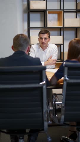Family with realtor in boardroom discussing about mortgage contract. Redhair female and her husband very interested in signing documetns in businesscenter. Vertical shot.