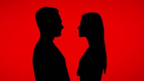 The silhouette of a couple touching each other's foreheads creates a romantic atmosphere against a bright red background - Powered by Shutterstock - Get 15% off with code: PIKWIZARD15