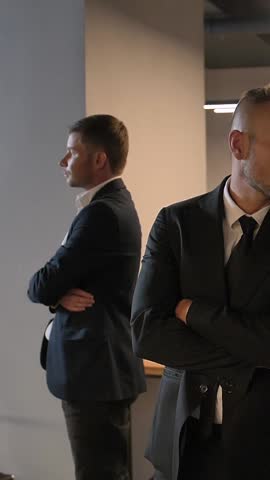 Cool Epic camera movement shot of 3 confident attractive handsome business people with serious faces. They turn their head to camera. Super slow motion 120 fps Vertical shot.