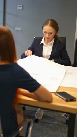 Confident businesspeople giving drawing presentation on drawings to colleagues, executive manager showing explaining new company strategy. Modern business center. Vertical shot.