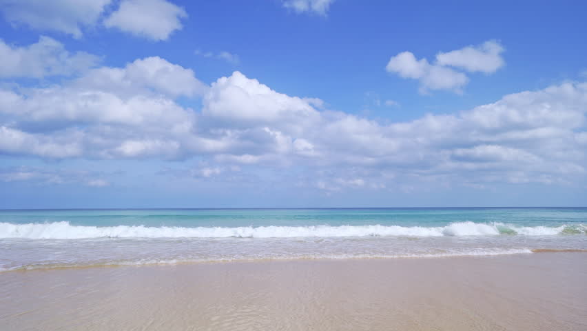 Summer sea background.Blue sky white clouds over ocean waves break on sand beach.Waves crashing against an empty beach.Sea waves and beautiful sand beach in Patong Phuket Thailand. High quality video 