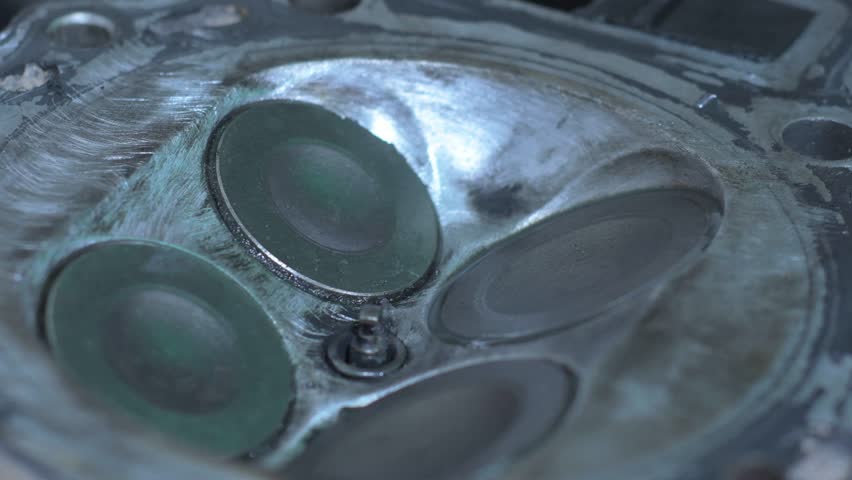 Close-up motorcycle engine cylinder head, showing valves opening and closing and surrounding metal