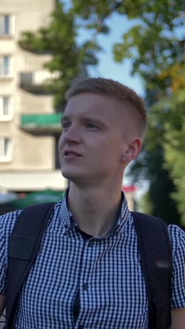 Young student photographer with digital camera in his hands walks around the small european town and photographs the sights. Culture and history interested young man concept. Vertical shot.